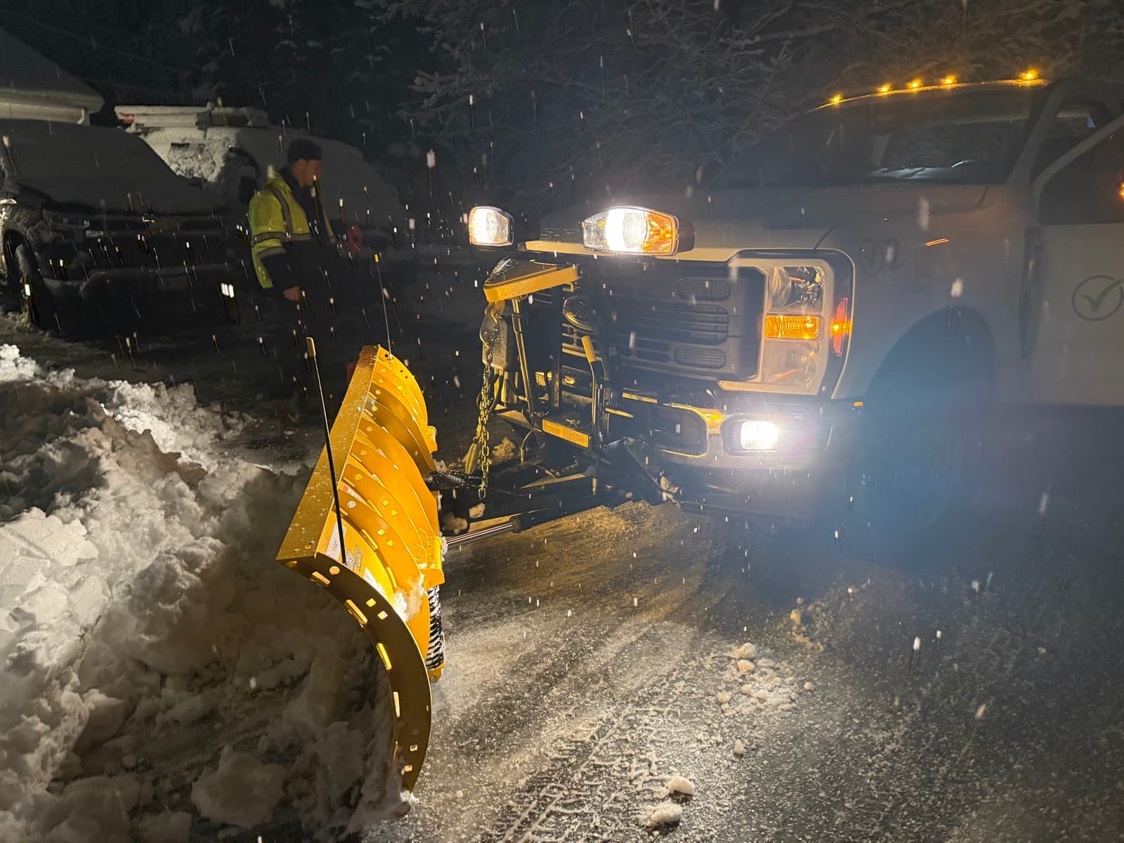 The LawnCheck plow up close, mid-storm, with a crew member working alongside