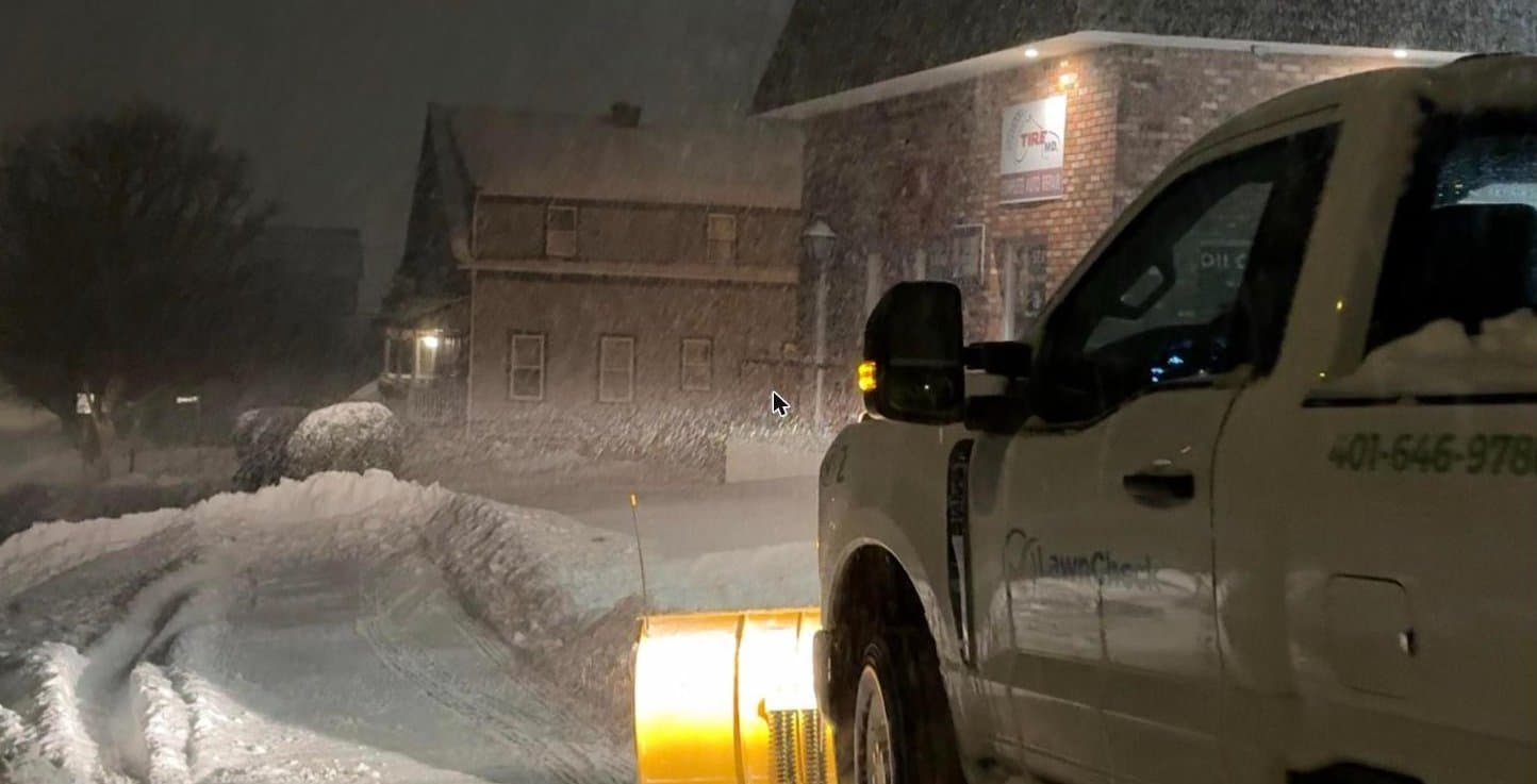 A LawnCheck plow truck arriving at a commercial property in driving snow