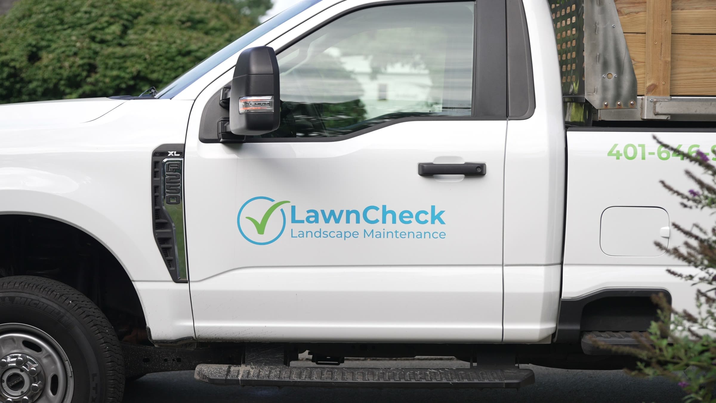 A branded LawnCheck truck on a property