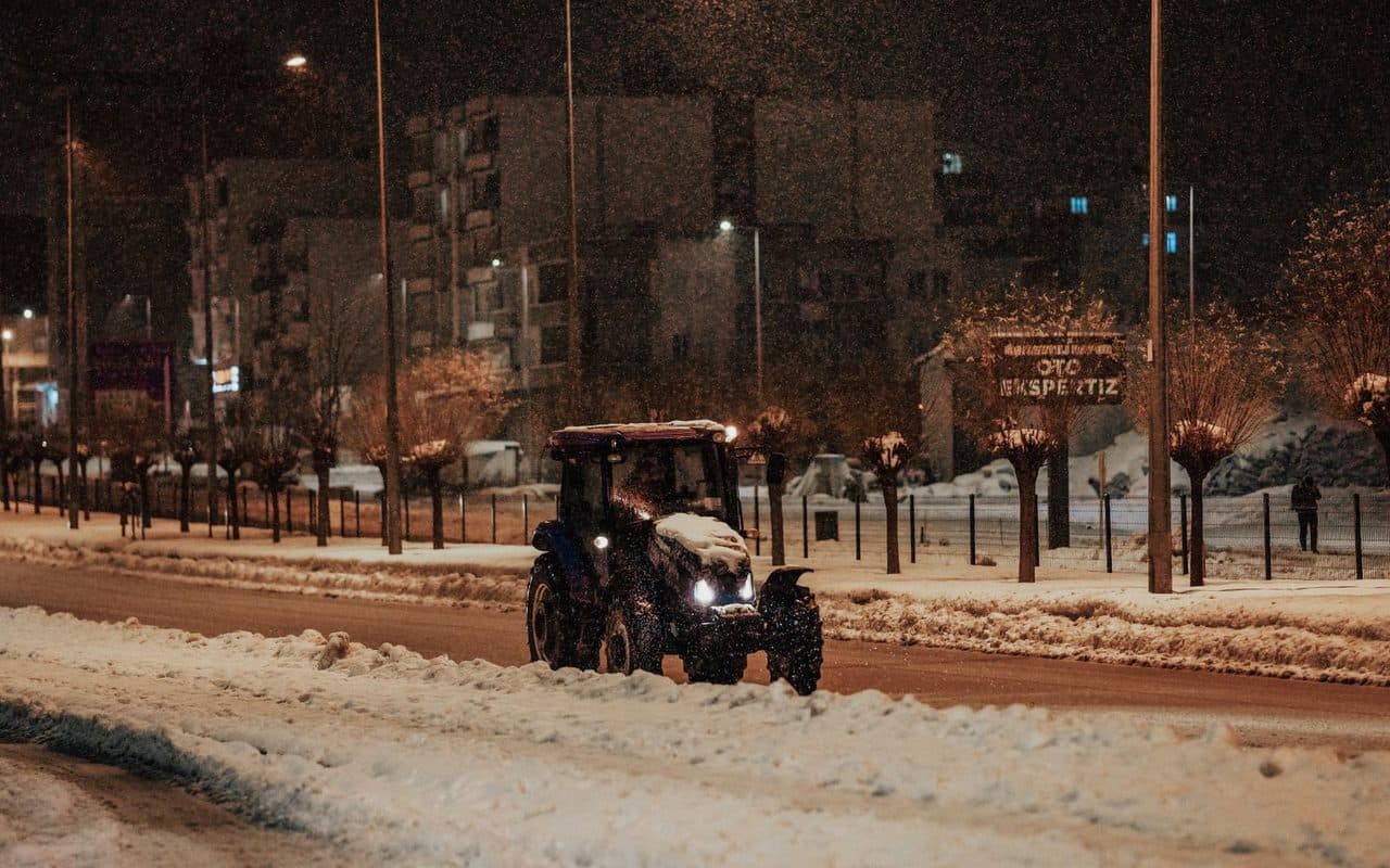 Plow trucks working under lights at night during an overnight snowstorm