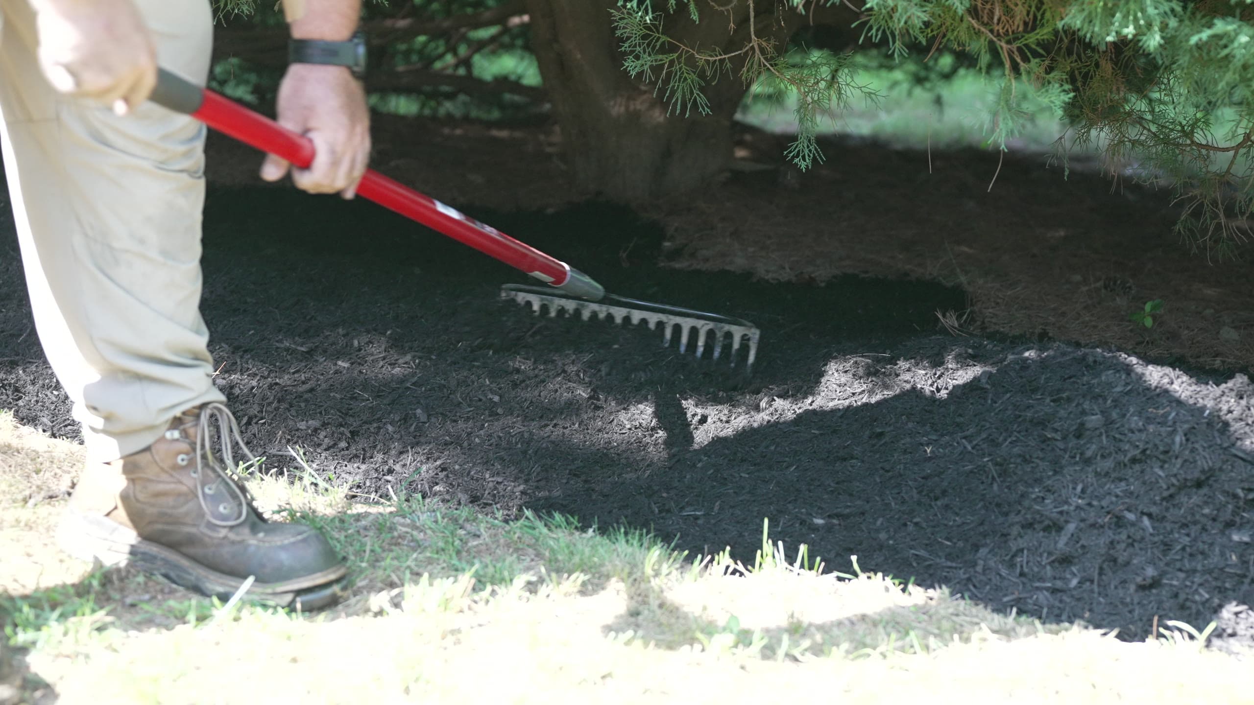 A rake spreading fresh mulch along a bed edge