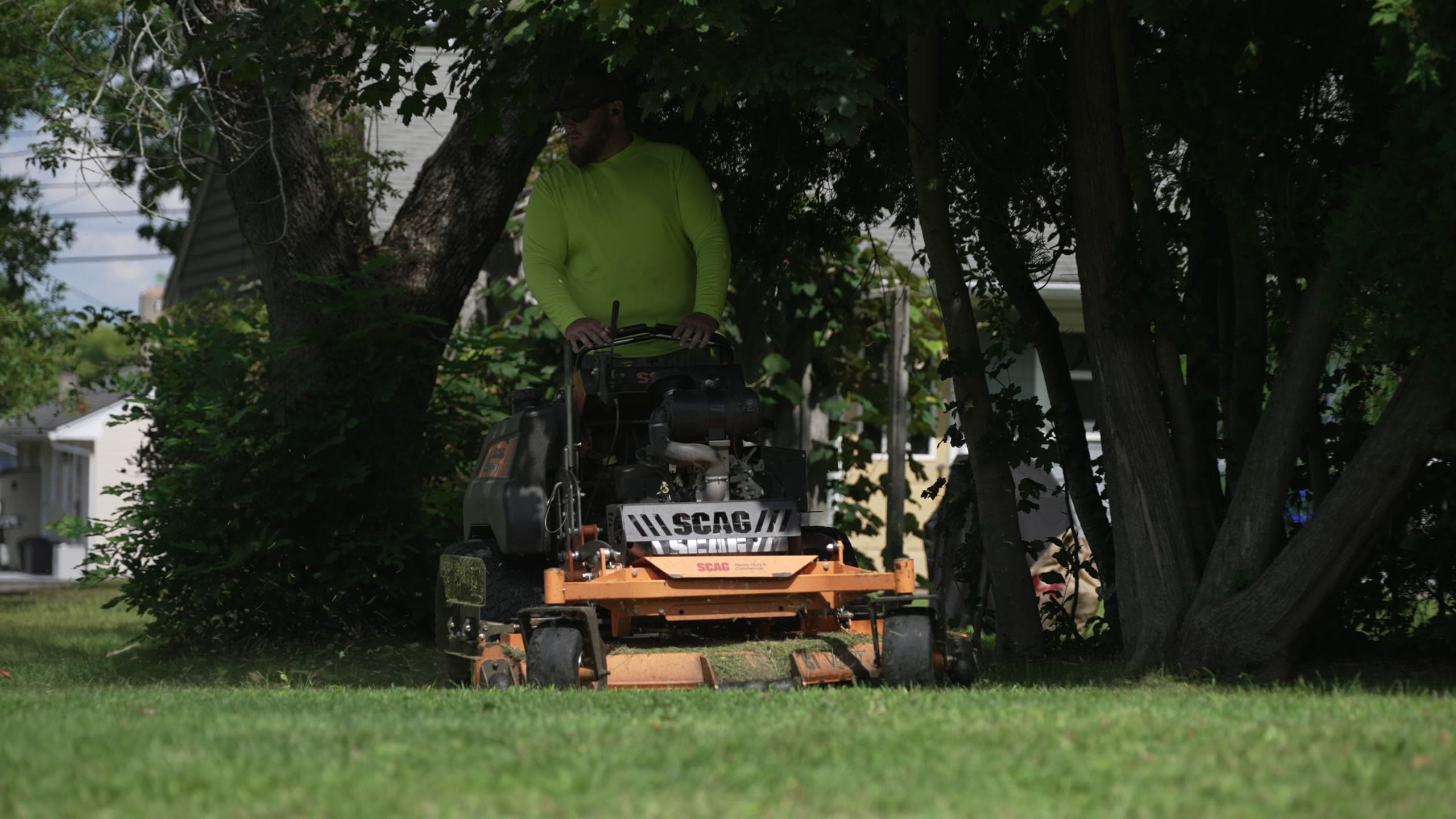 A crew member mowing under the tree canopy of an East Bay property in summer