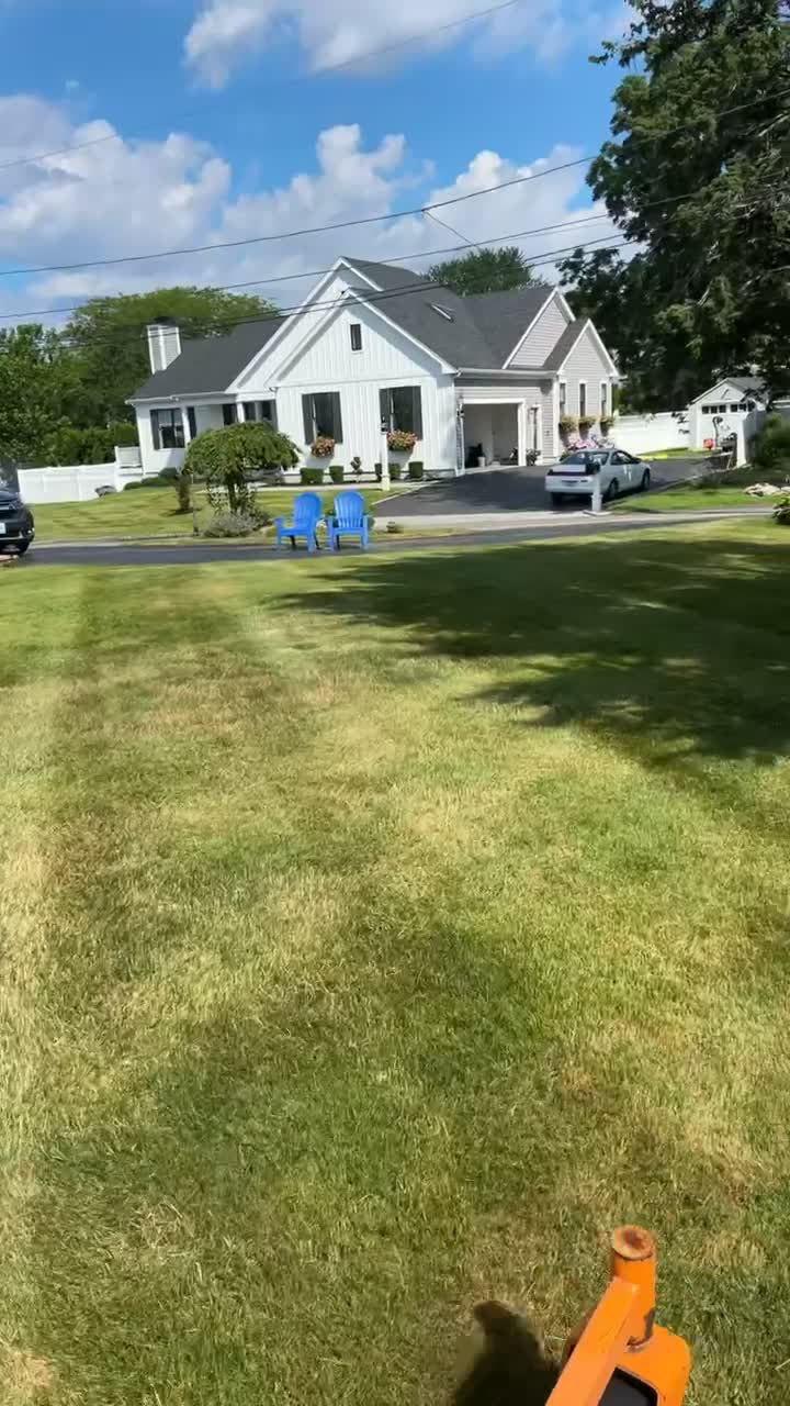 Mowing a deep green lawn toward a white East Bay farmhouse on a clear summer day